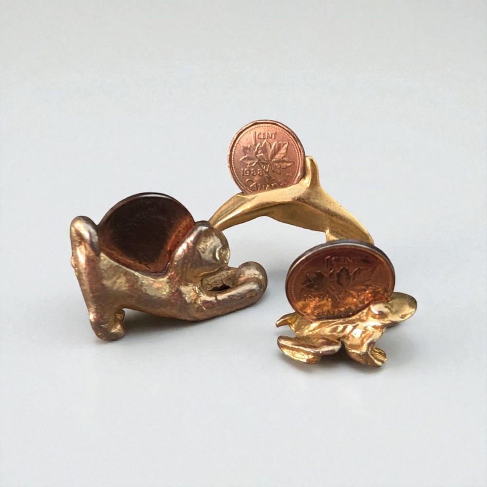 3 gold coloured/toned souvenir animals with Canadian pennies on their back